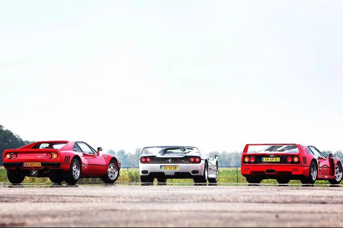 Rear view of a red 288 GTO with registration NJ-89-LH beside a silver open Ferrari and a red F40